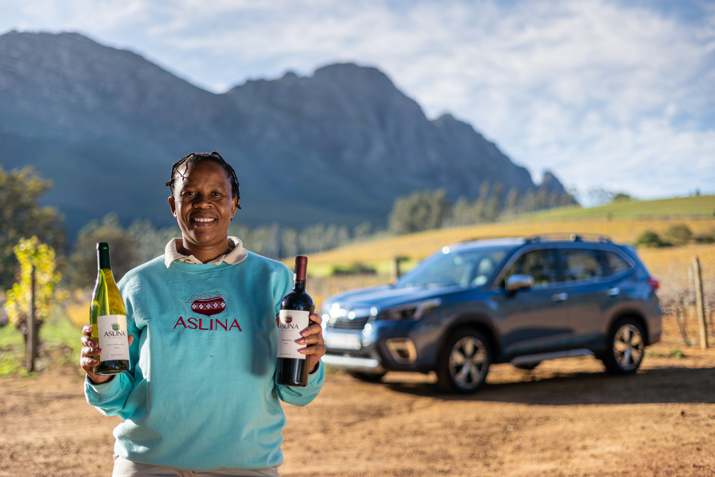 Woman Holding Bottles Next To Subaru Forester